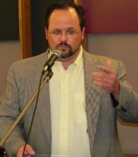Chef Chris Villa speaking at a podium with microphone